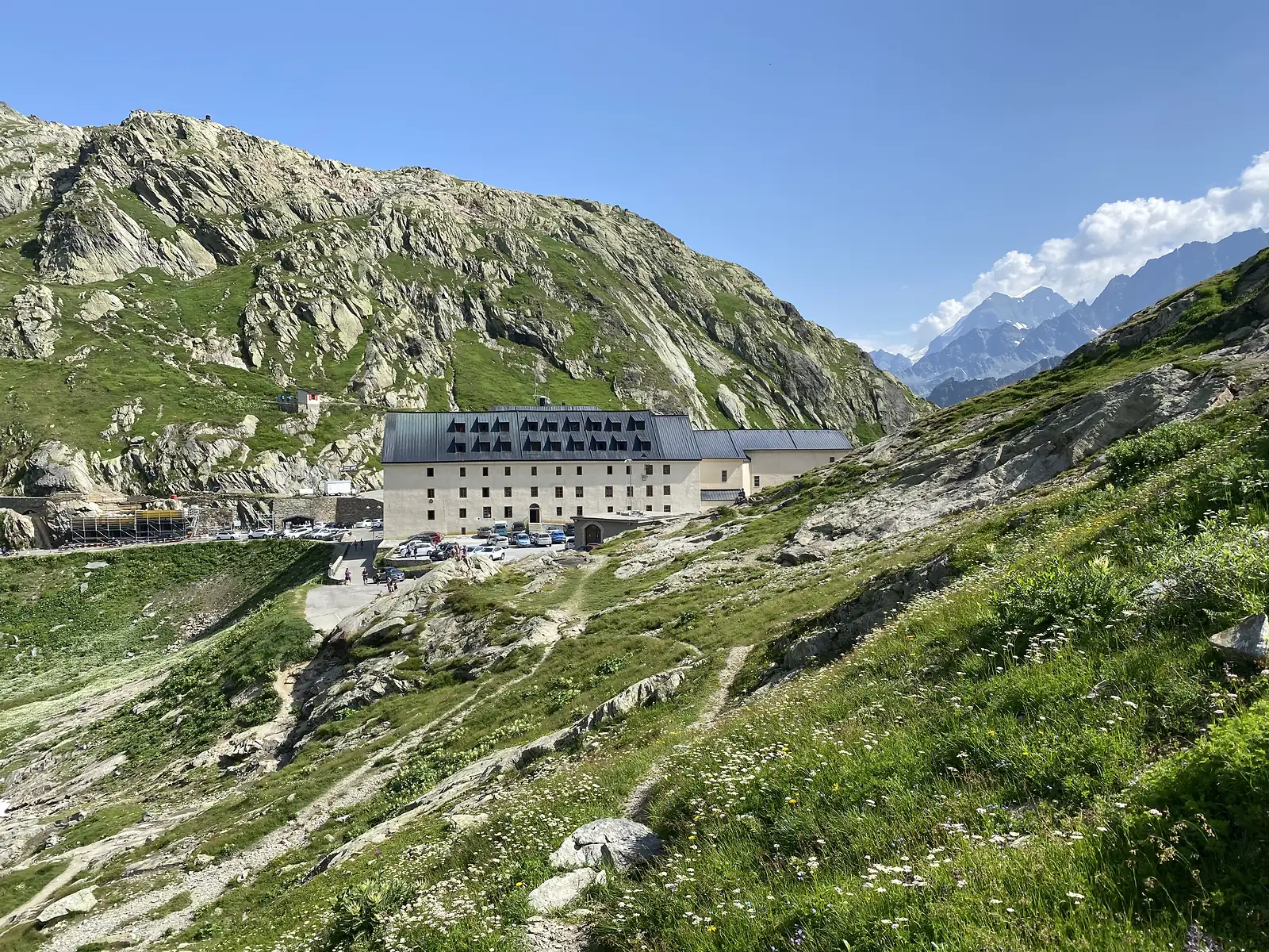 A long stone hospice building with a steeply pitched, dormer-lined roof set against bare rocky mountainsides near the Col du Grand-Saint-Bernard.