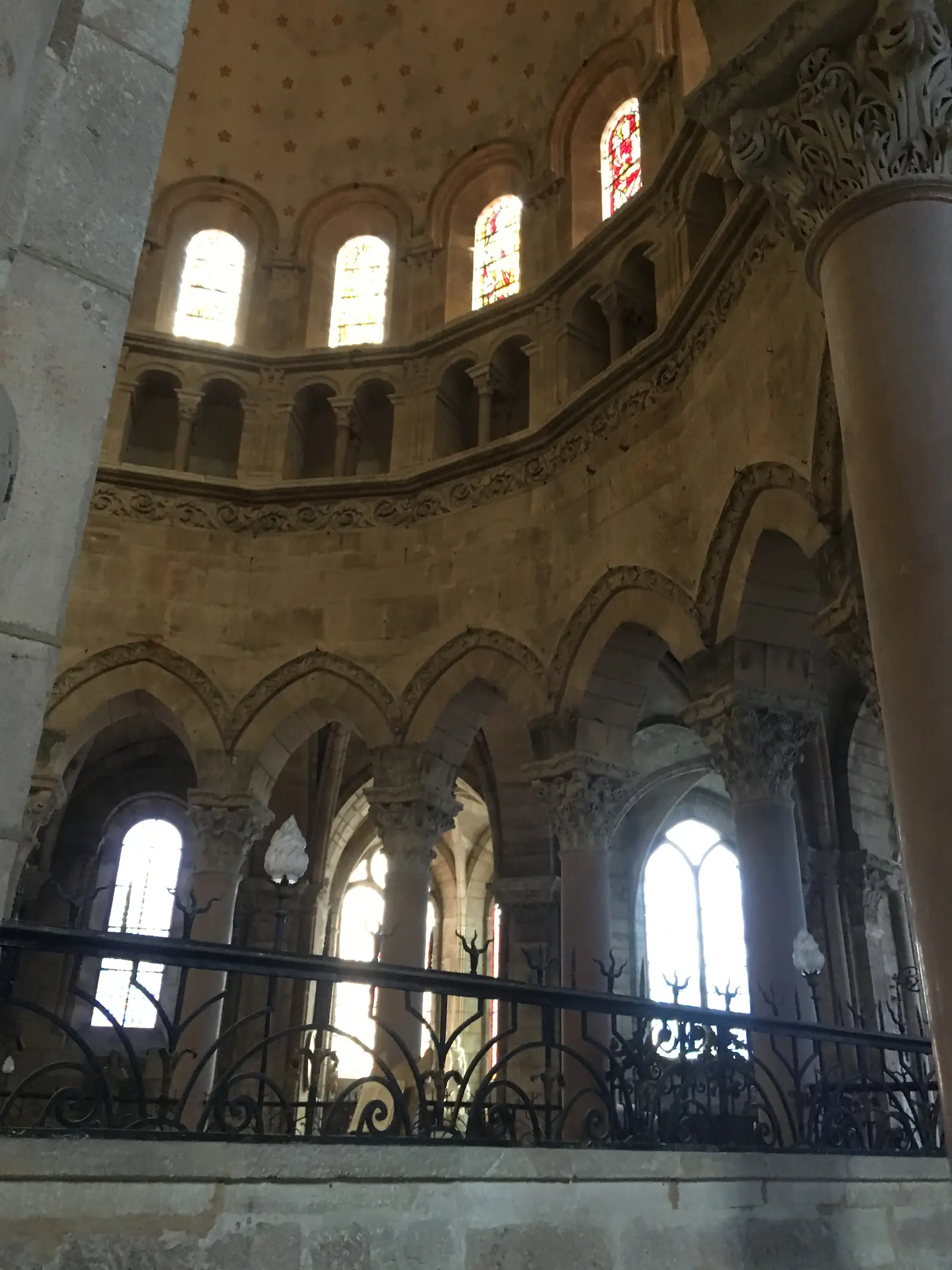 The vaulted ceiling and clerestory windows of a Gothic church interior, seen from beside a wrought-iron chancel screen and stone column.