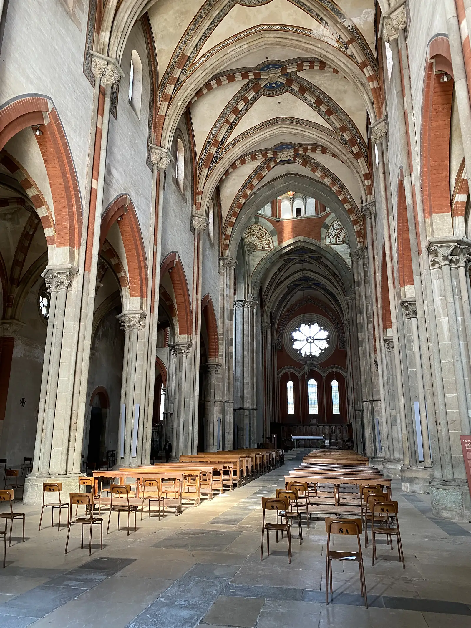 Looking up into the ribbed, red-and-white striped vaulting of the basilica's nave, with rows of numbered choir stalls below.