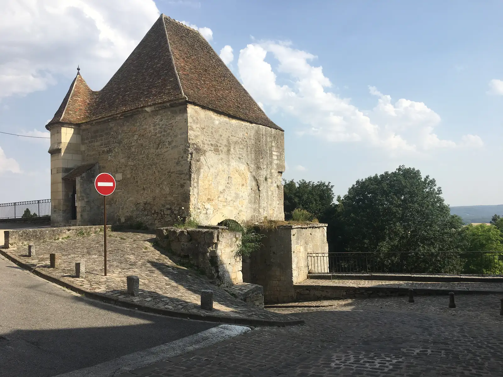 A stone corner tower with a steep conical roof and a small turret marks the edge of the old town, a no-entry sign fixed to its wall.