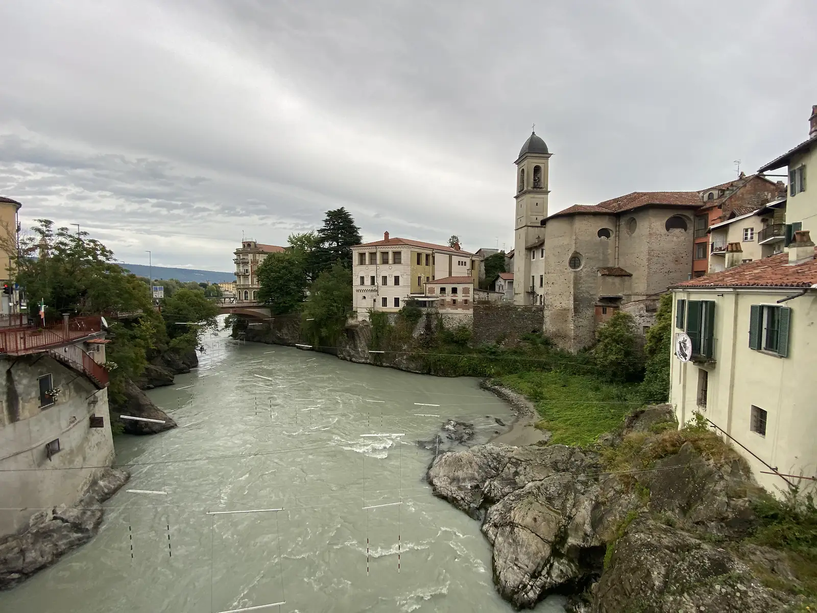 A river running through a rocky gorge overlooked by a bell tower and clustered old townhouses with terracotta roofs on either bank.