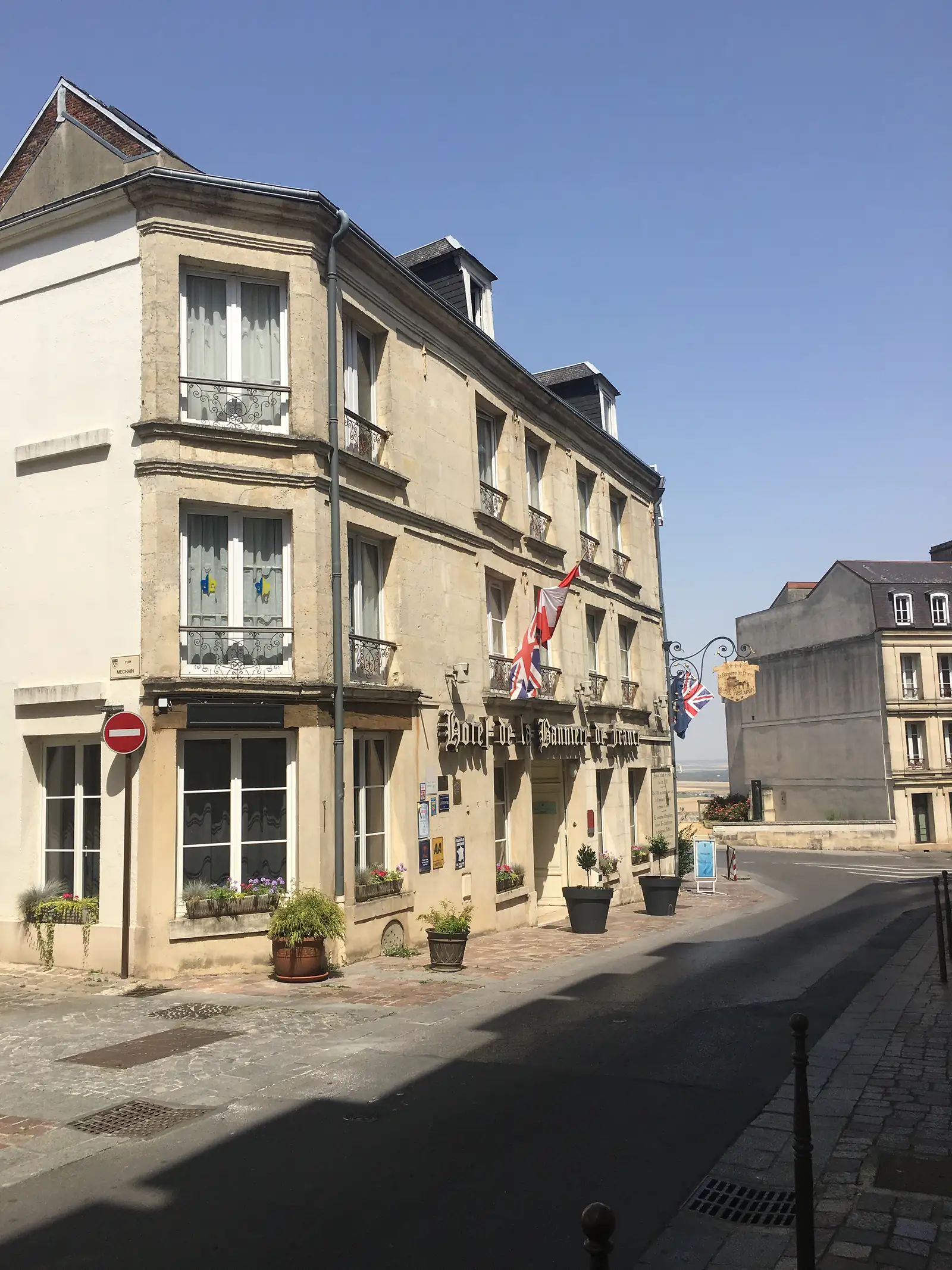 The stone facade of the Hôtel de la Bannière de France rises above its sign, with a Swiss flag and a Union flag hanging from the upper windows.