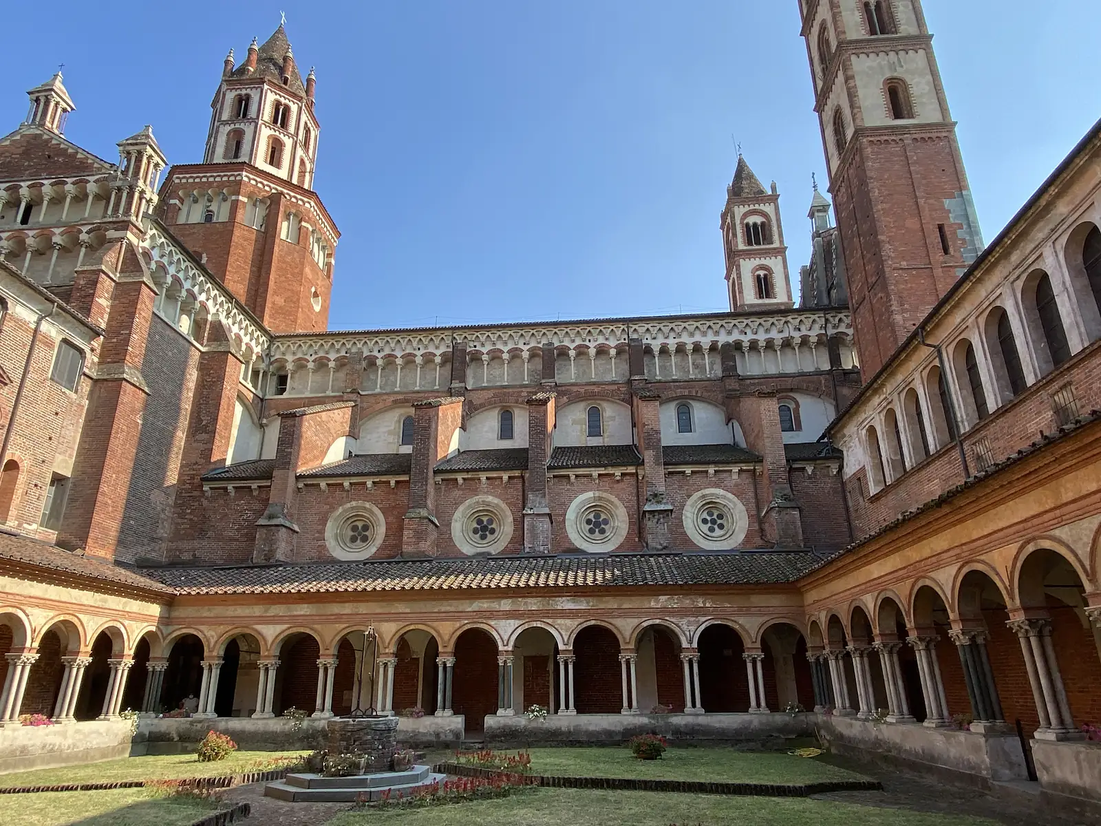 The grey stone west front of the Basilica of Sant'Andrea, its twin towers and central rose window rising above a scattering of visitors on the piazza.
