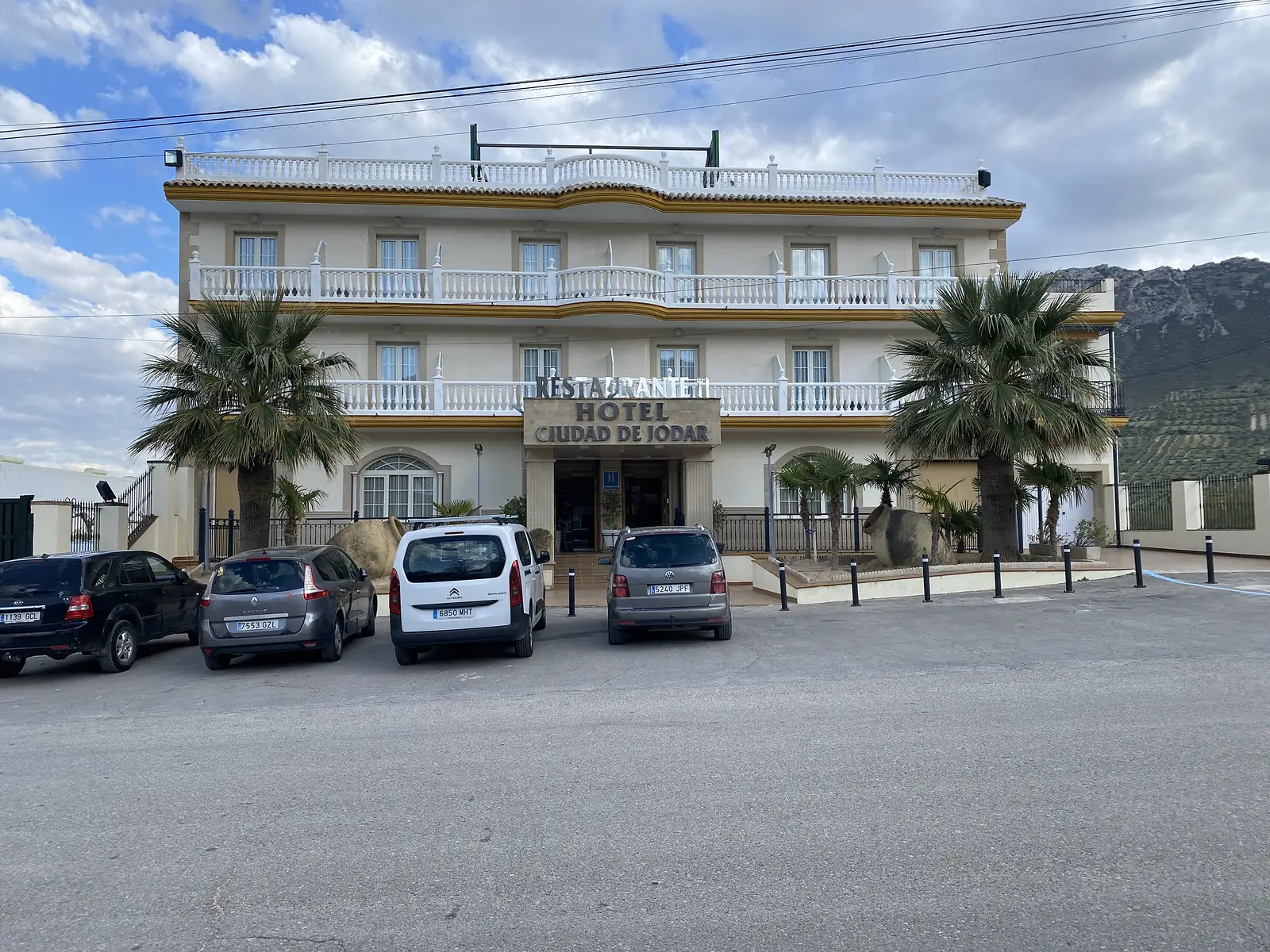 A three-storey white hotel with balustraded balconies and palms outside, lettered "HOTEL CIUDAD DE JODAR" above the entrance.