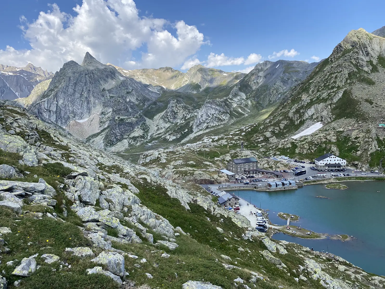 A dramatic view over jagged, snow-streaked peaks down to the hospice buildings, lake and car park nestled in the valley below.