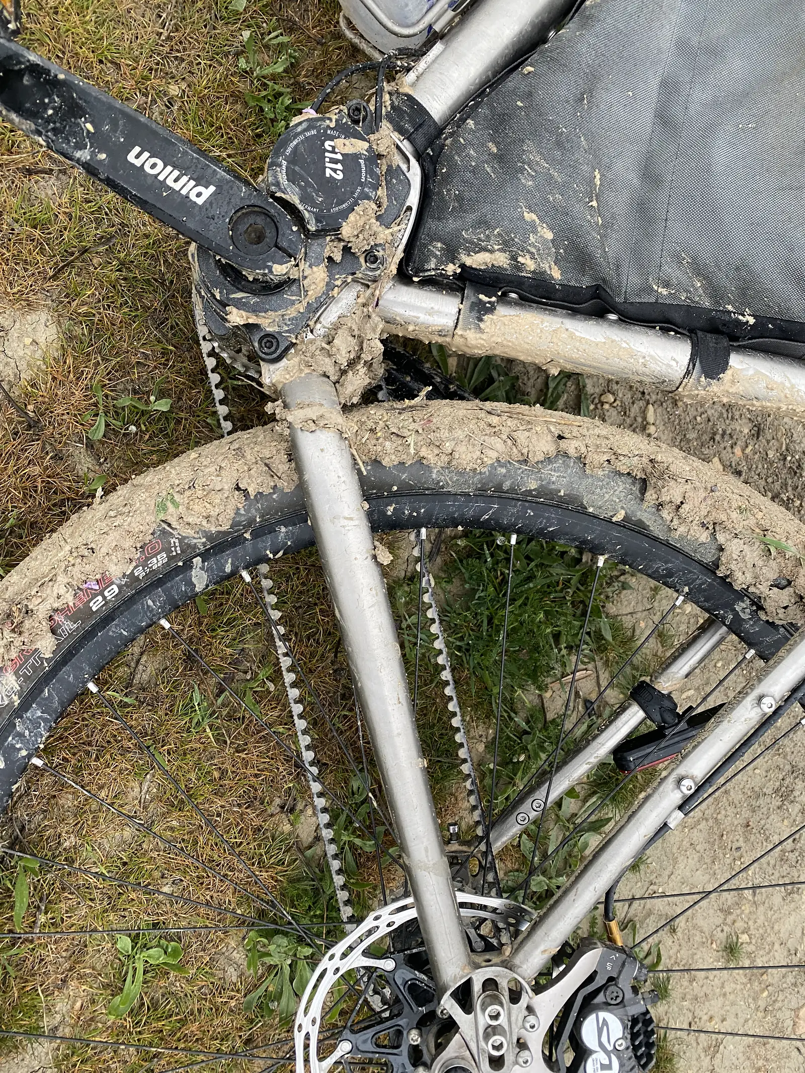 A bike's cranks, chainring and front wheel caked solid with thick pale mud, the tyre tread completely clogged.