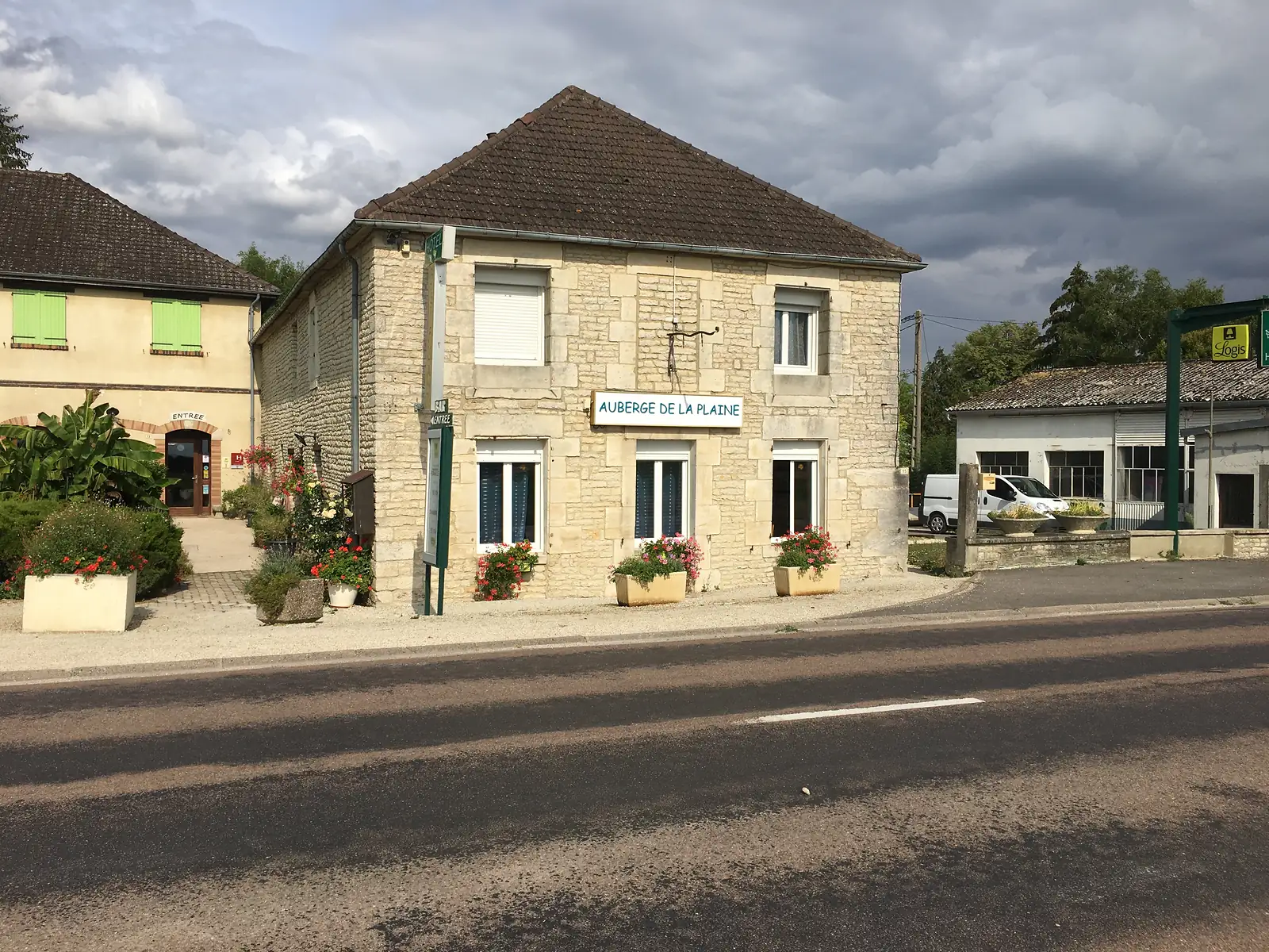 The Auberge de la Plaine, a stone-built inn with shuttered windows and flower-filled planters, stands on a village street corner.