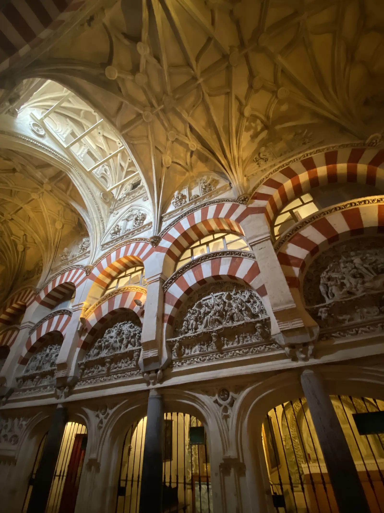 Red-and-white striped arches filled with carved stone reliefs, rising to a ribbed vaulted ceiling.