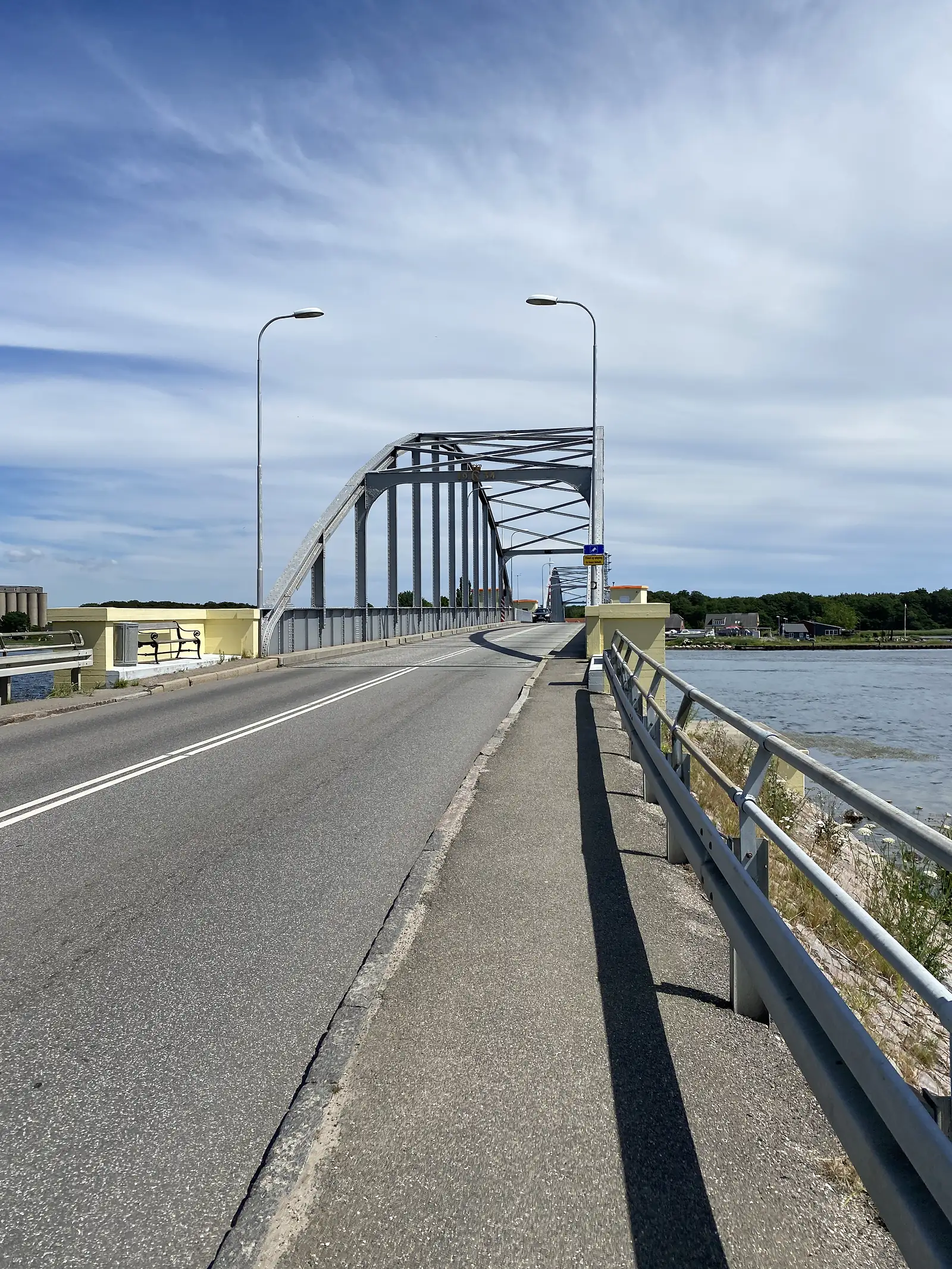 A steel arch road bridge crossing a channel, with a cycle path running alongside the carriageway.