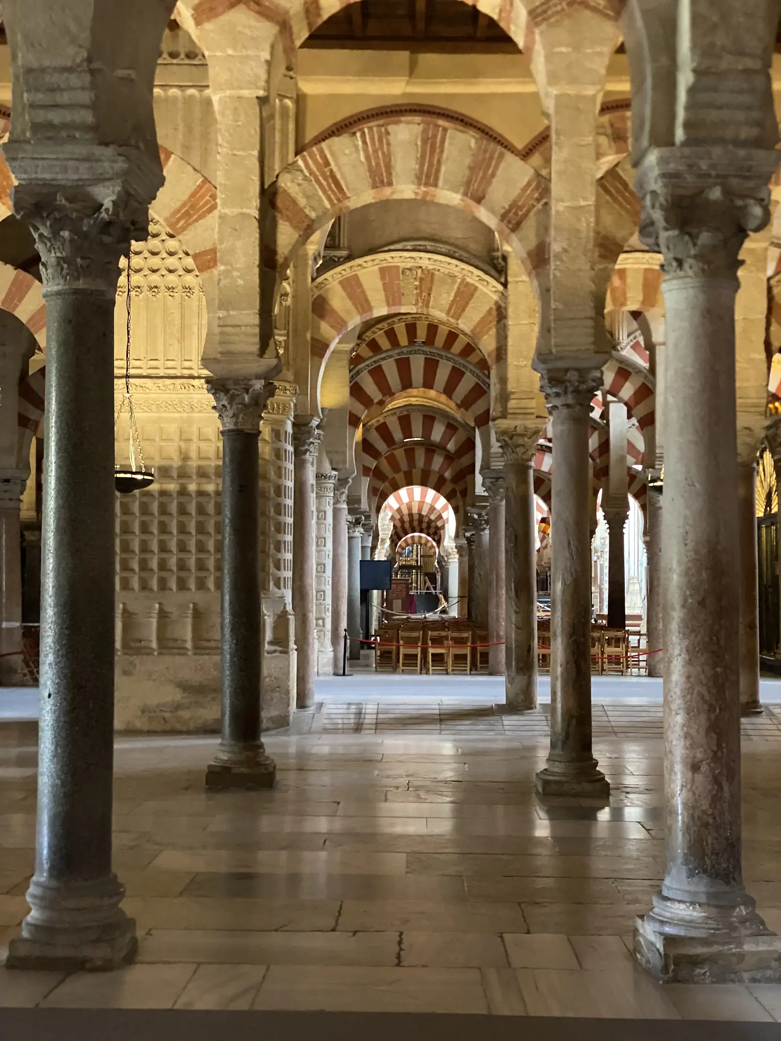 A forest of marble columns carrying tiers of red-and-white striped horseshoe arches in a vast mosque-cathedral hall.