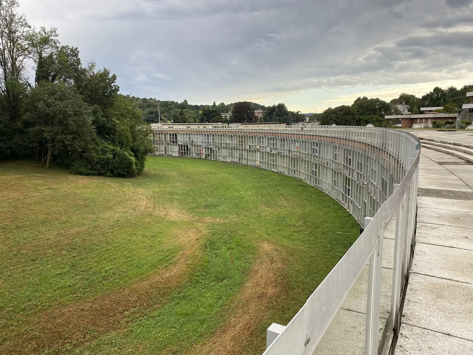 A grassed mound with domed rooflights set into it, a white railing curving along the top of a roof terrace above gated tunnel entrances below.