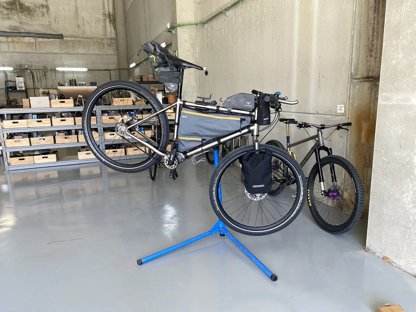 A silver bike with a frame pack on a blue maintenance stand.