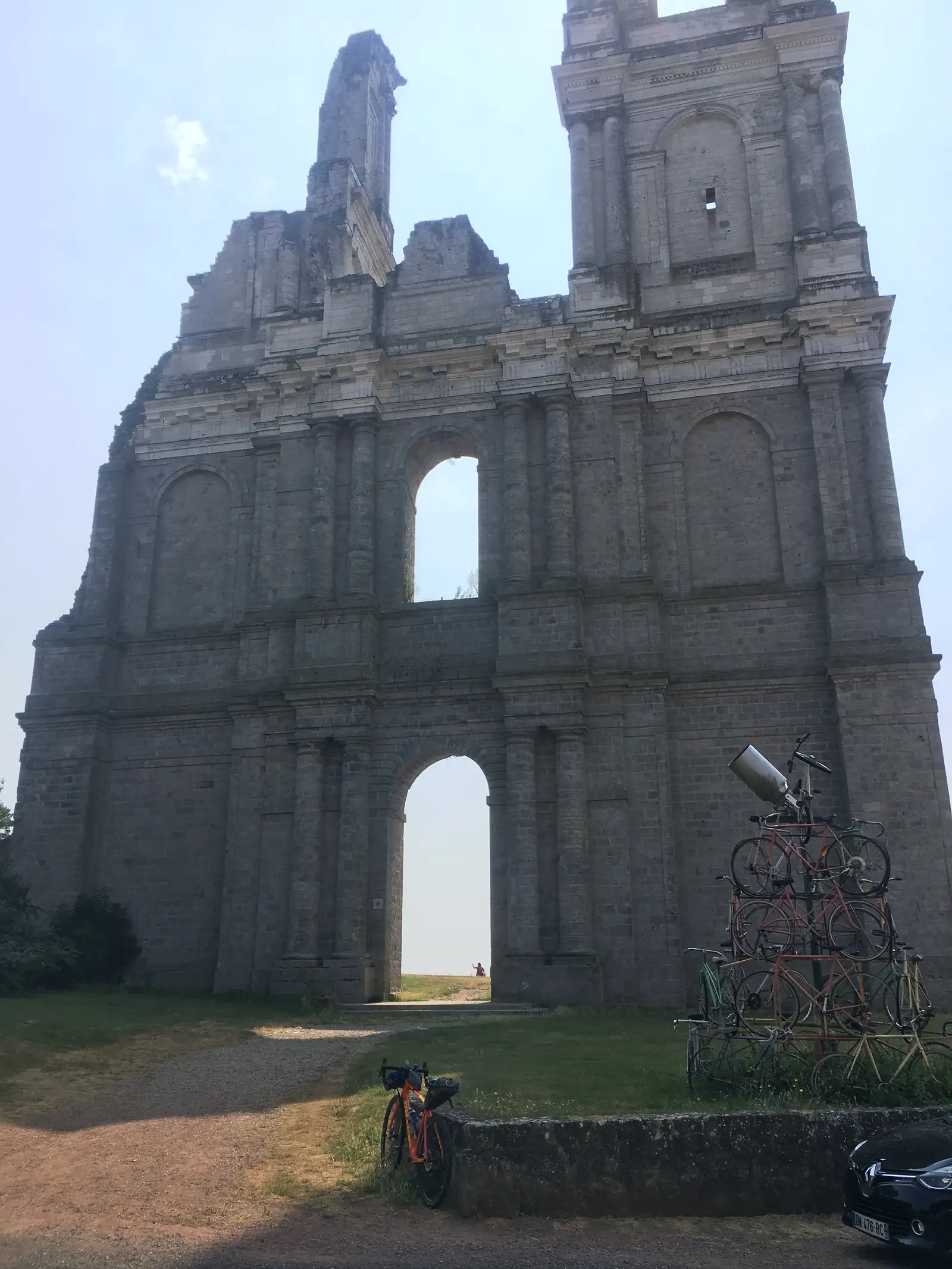 The ruined arches and stonework of a bombed church, with a laden touring bicycle parked in the grass beside a row of bikes chained to a rack.
