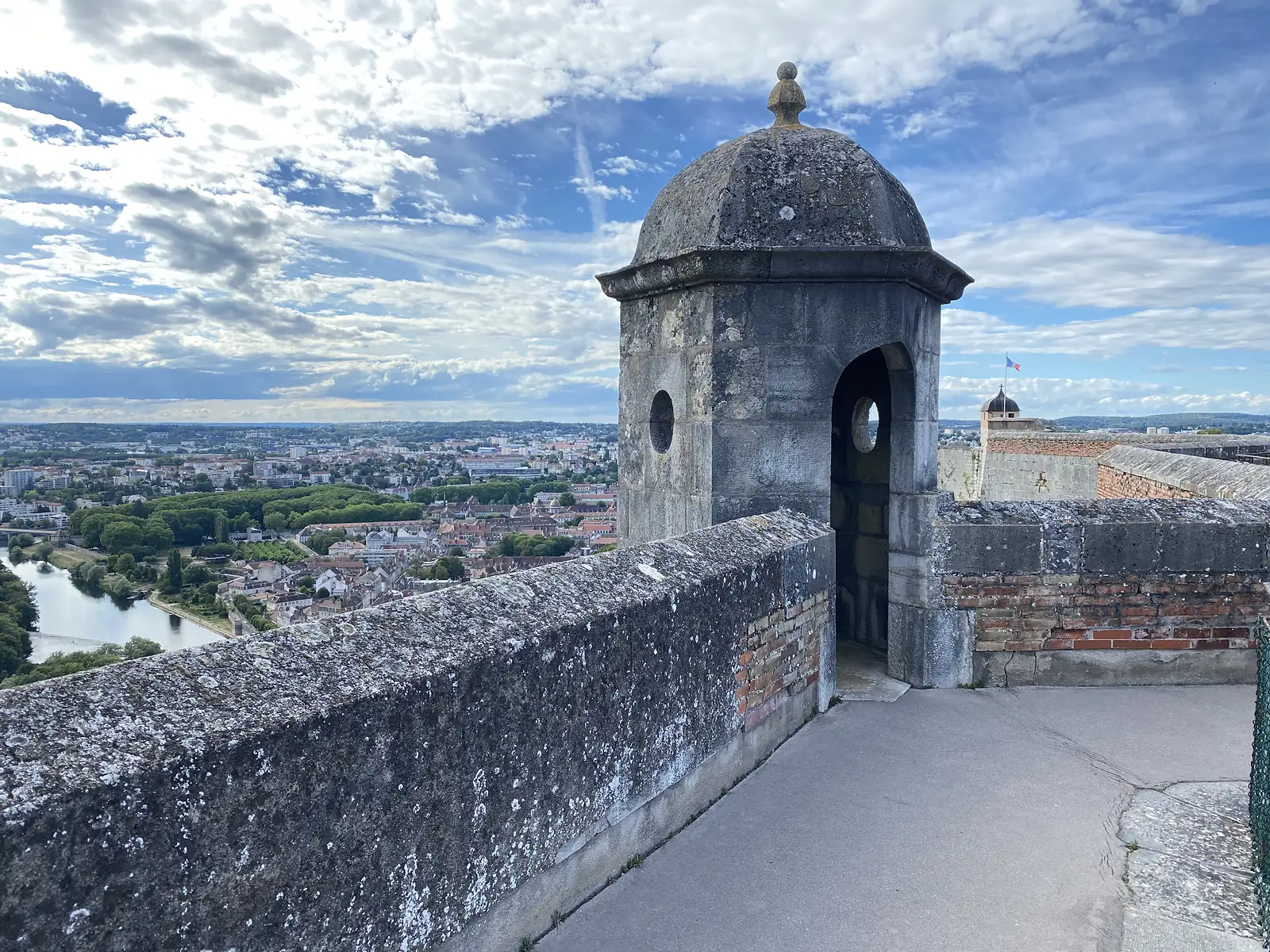 A stone sentry box with an open archway stands on the citadel's ramparts, overlooking rooftops and the river below.