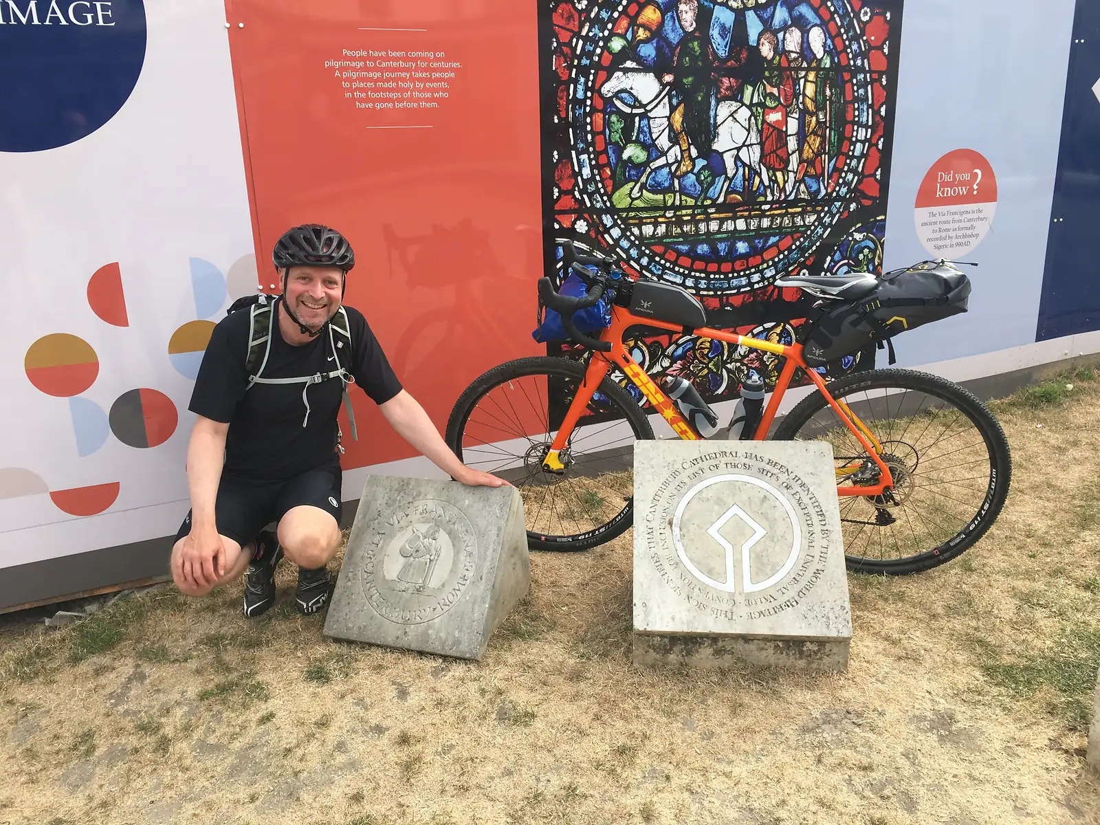 Bloke and orange bike and the km 0 sign of the Via Francigena