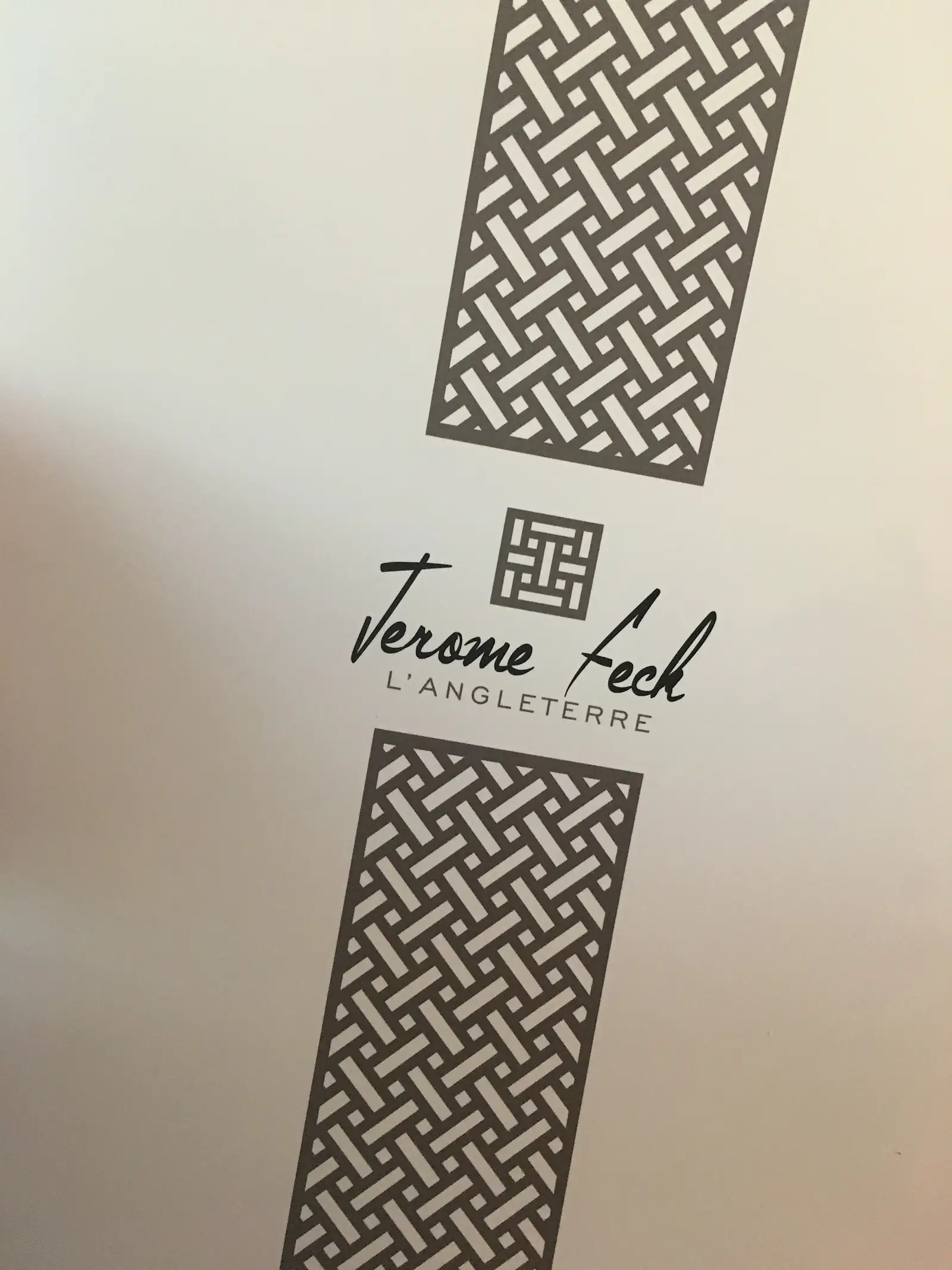 A restaurant menu card printed with a woven basketweave pattern and the signature 'Jerome Feck, L'Angleterre'.