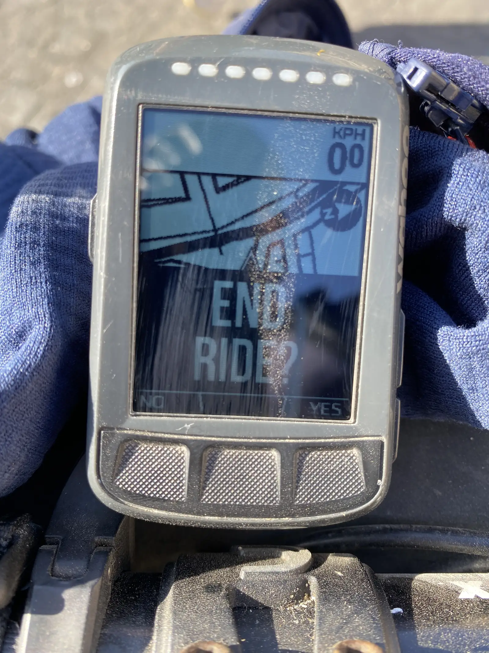 A handlebar-mounted cycling computer reading "00 KPH" with an "END RIDE?" prompt on screen, marking the finish of the day's ride.